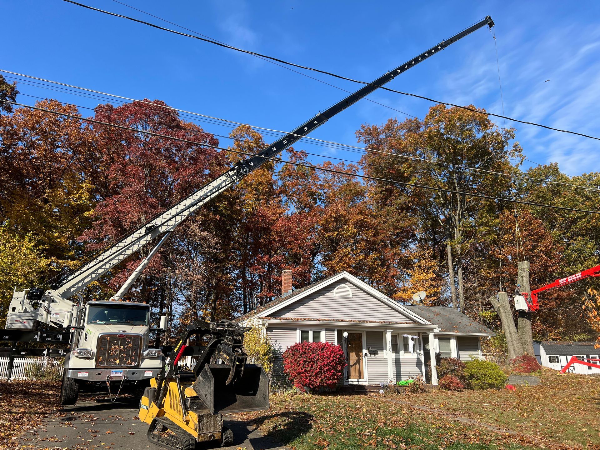 A truck with a crane on top of it is parked in front of a house.