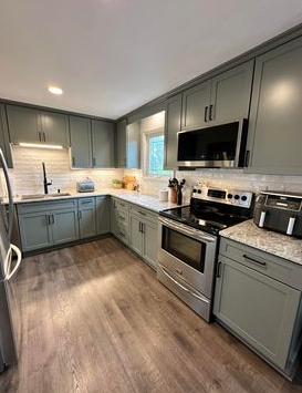 Modern kitchen with gray cabinets, stainless steel appliances, and a wood-look floor