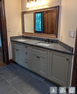 Built-in bathroom vanity with gray cabinets, stone countertop, large mirror, and dark tile floor.