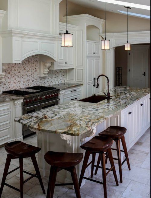 Elegant white kitchen with marble island, pendant lights, and three stools