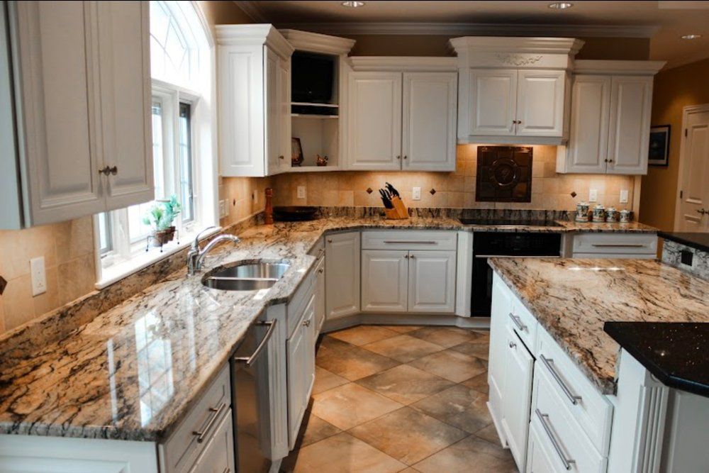 Bright kitchen with white cabinets, granite countertops, stainless sink, and tiled floor.