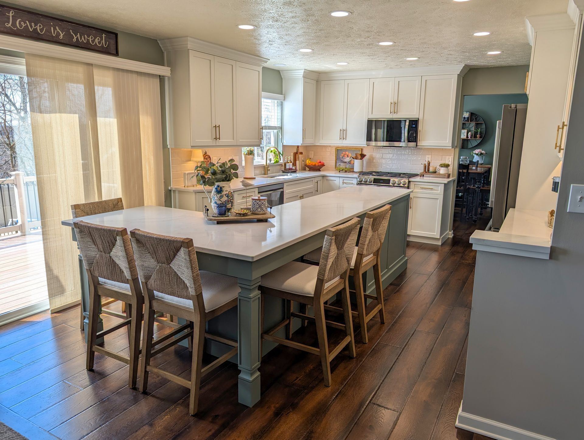 Bright kitchen with large island, white cabinets, wood floors, and sliding glass doors to a patio