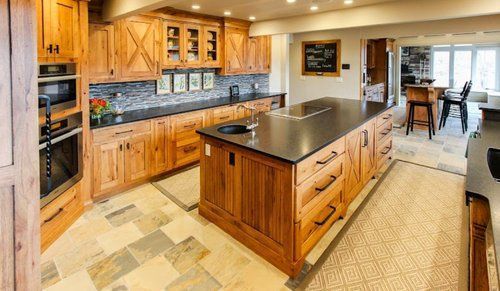 Spacious modern kitchen with wood cabinets, black island countertop, and open dining area beyond