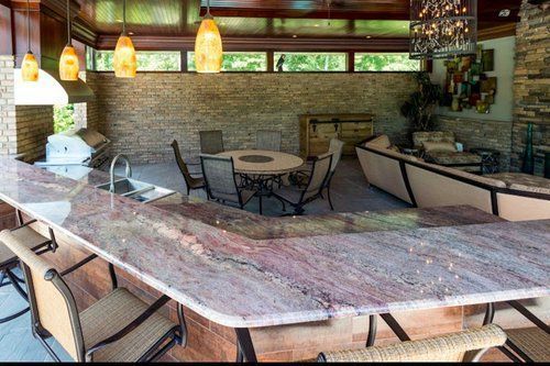 Outdoor covered patio dining area with stone bar, round table, and hanging pendant lights