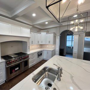 Bright modern kitchen with white cabinets, marble island, stainless steel range, and arched doorway