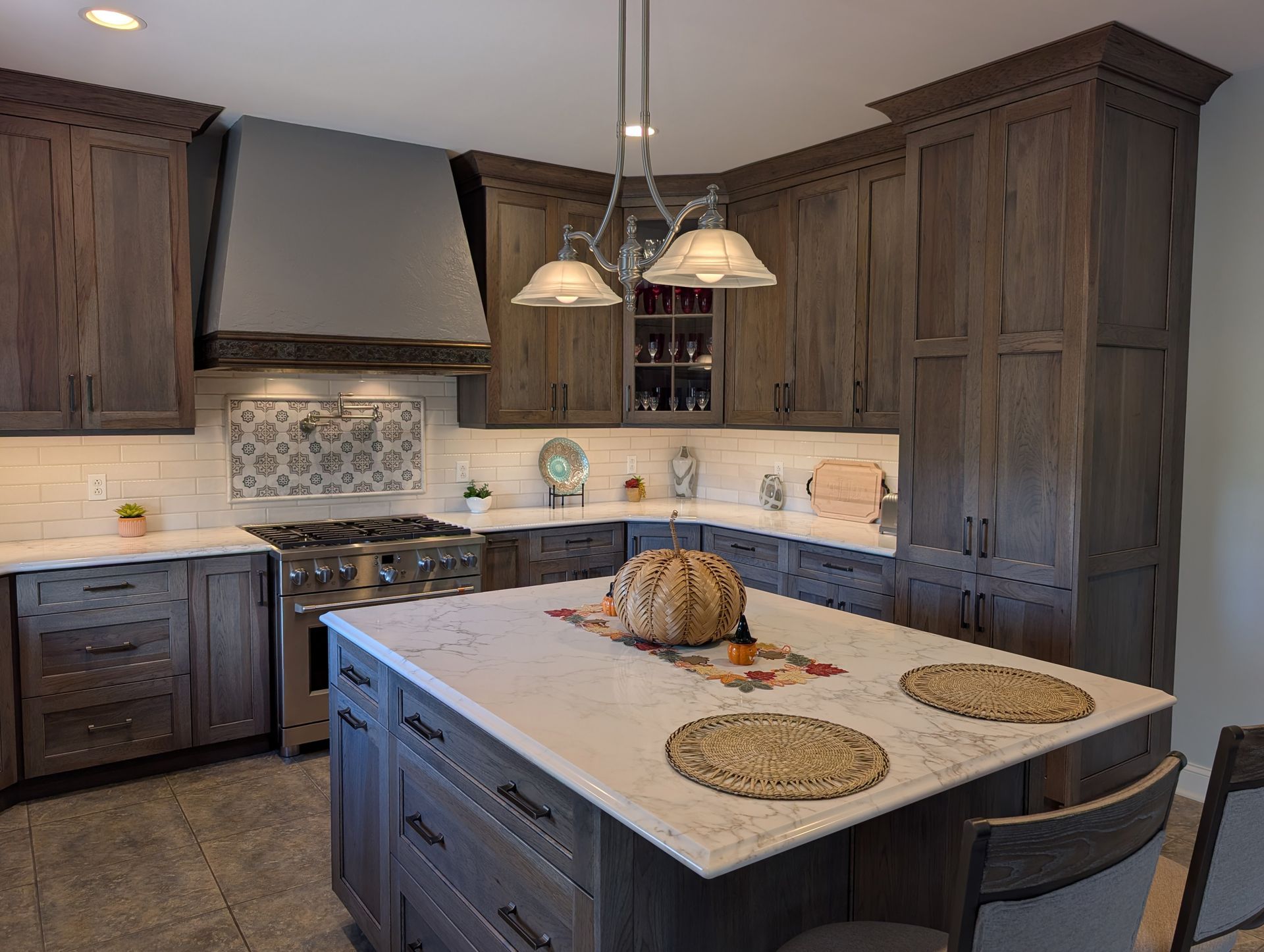 Modern kitchen with dark wood cabinets, island, pendant lights, and tiled backsplash
