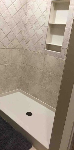 Tiled shower stall with a white bench seat and built-in corner shelf.