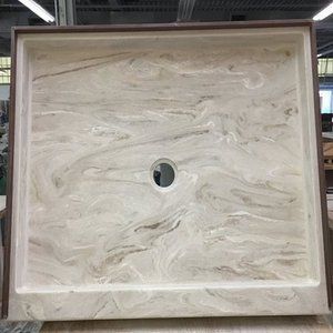 Square beige stone basin with a central drain hole