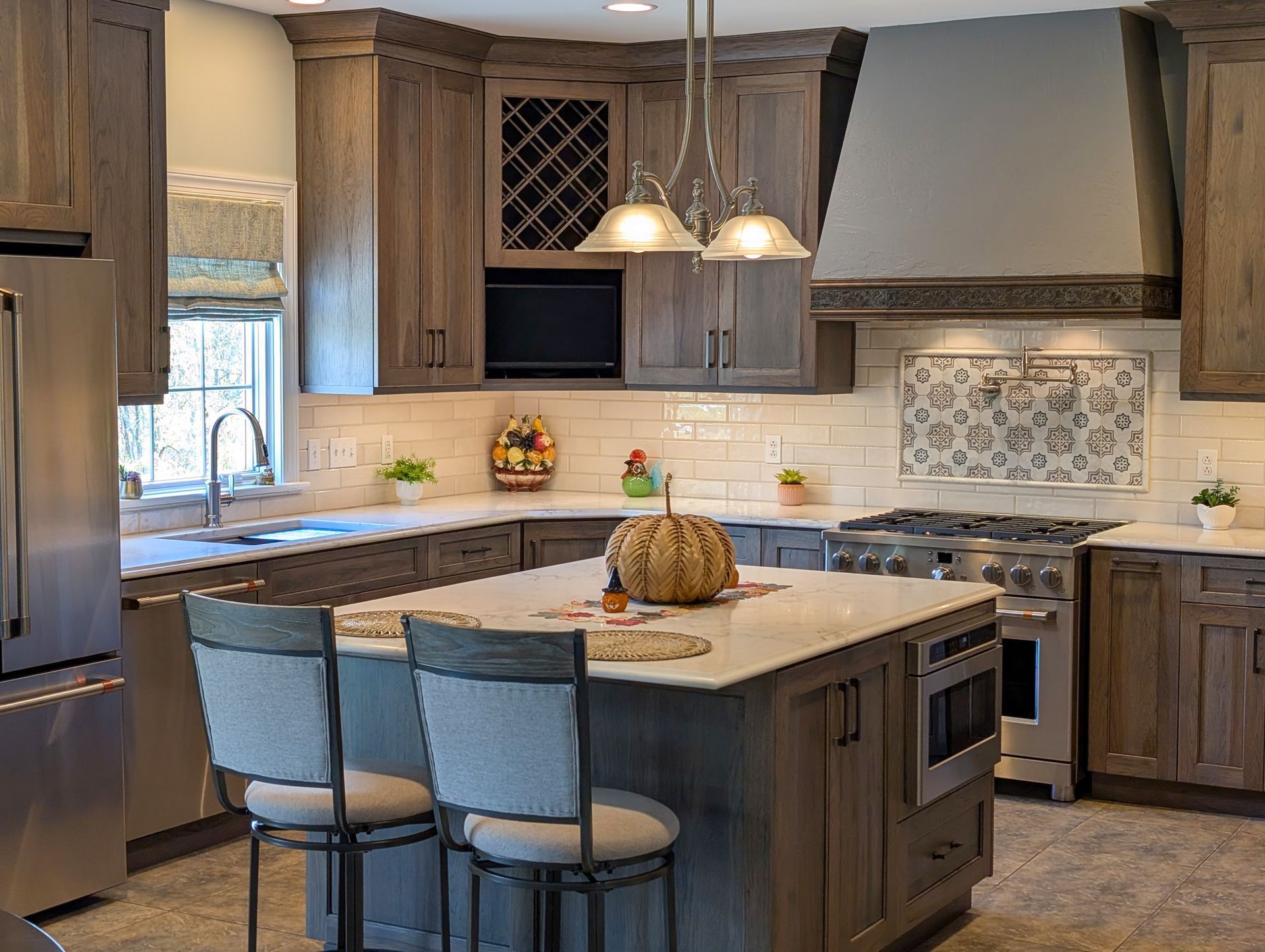 Modern kitchen with gray cabinets, marble island, pendant lights, and stainless steel appliances