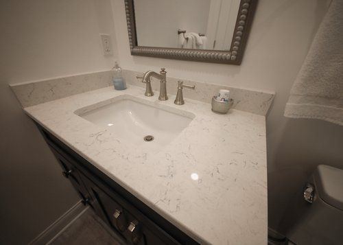 White bathroom vanity with sink, mirror, and chrome faucet under soft lighting