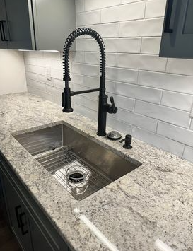 Modern kitchen sink with black spring faucet, granite countertop, and white subway tile backsplash