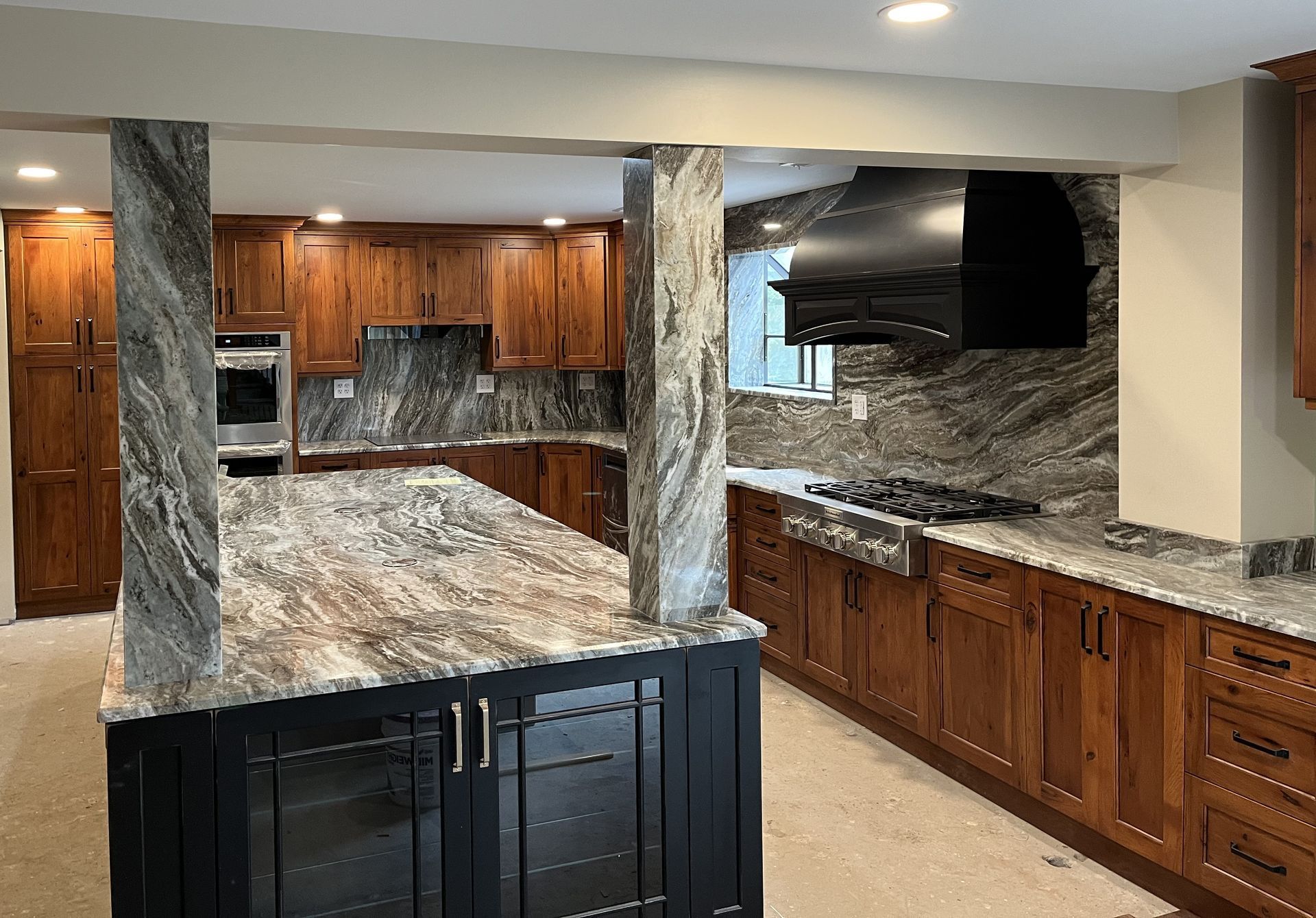 Luxury kitchen with wood cabinets, marble island, and granite backsplash under warm lighting