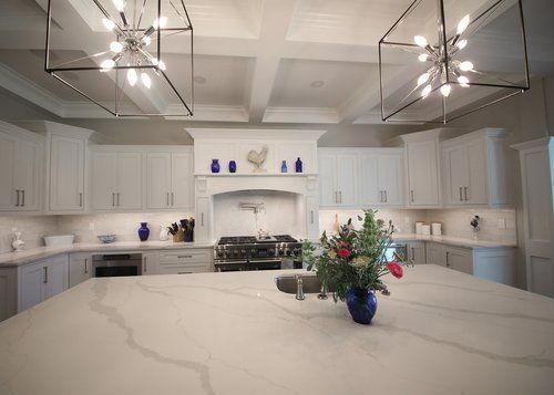 Bright modern white kitchen with large island, blue accents, and pendant lights