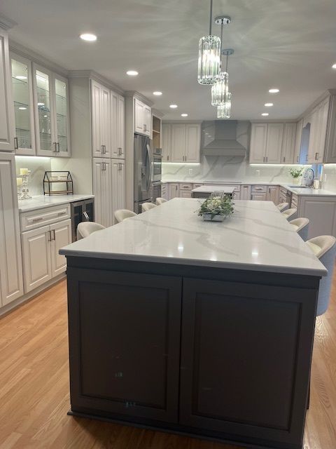 Modern kitchen with a dark island, white marble countertop, gray cabinets, and pendant lights