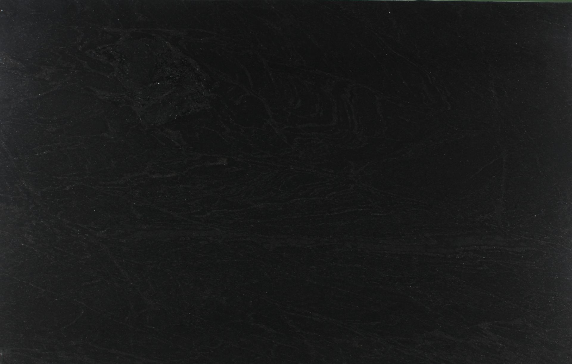 Dark, nearly black textured surface with faint horizontal scratches.