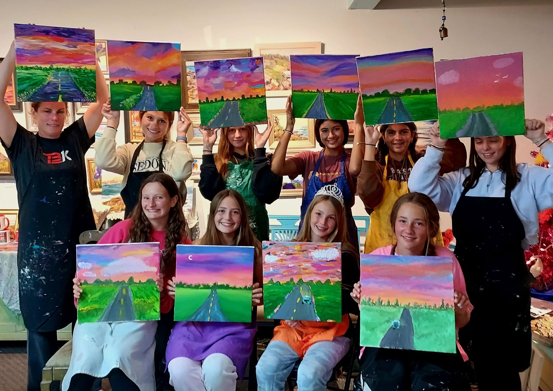 A group of young people holding up paintings of a road