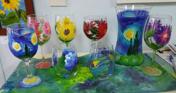 A table topped with a variety of hand painted wine glasses.