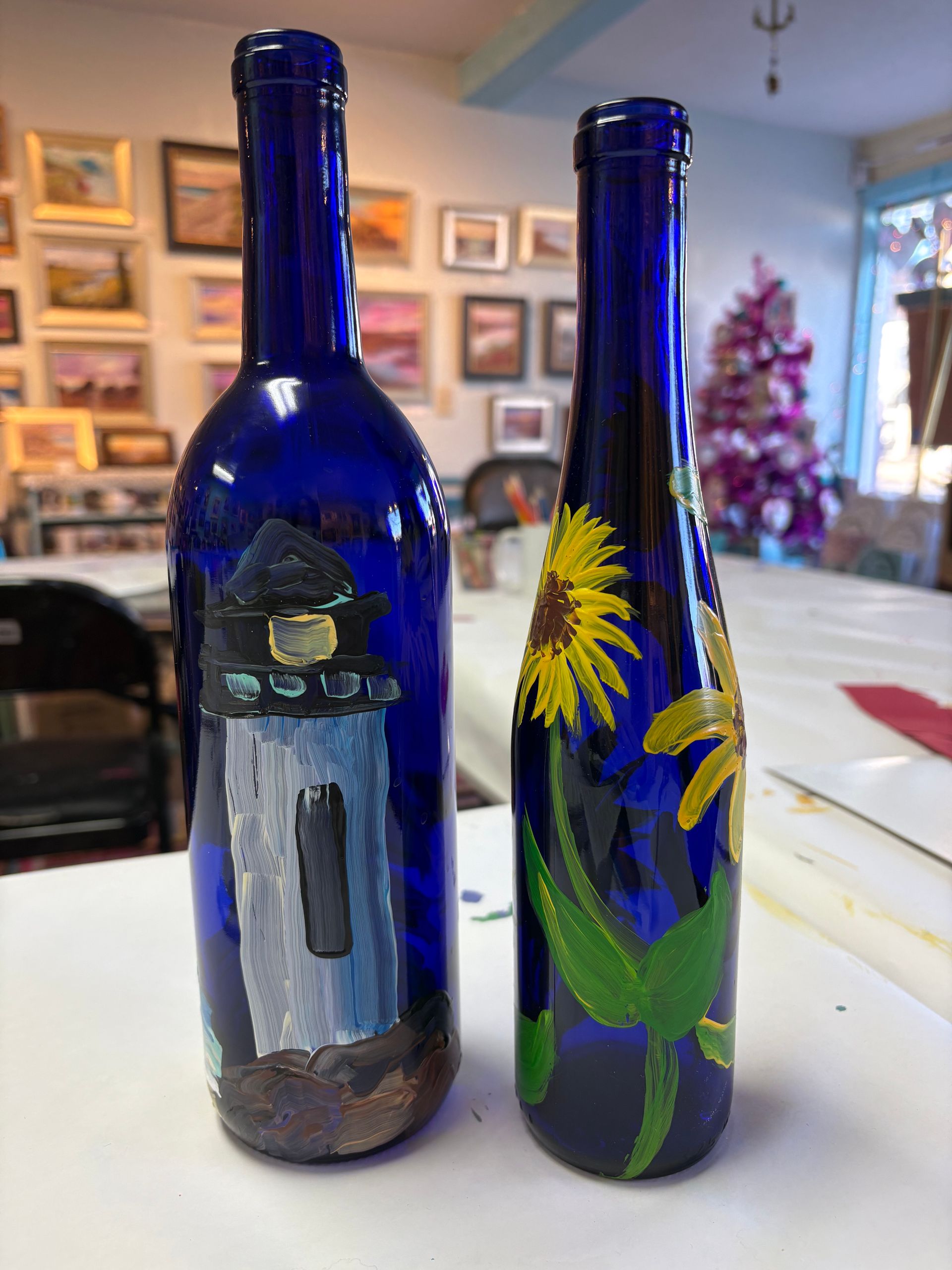 Two blue bottles with sunflowers painted on them are sitting on a table.