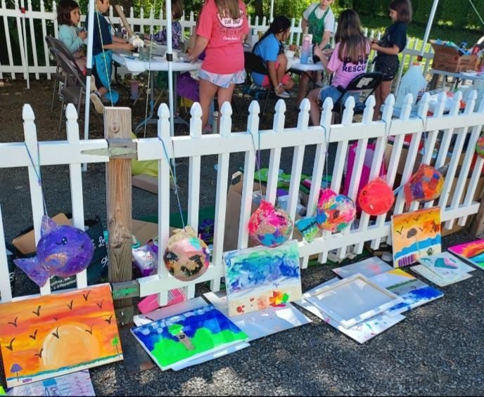 A white picket fence with a bunch of paintings on it