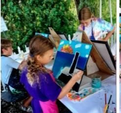 A group of children are sitting at a table painting.