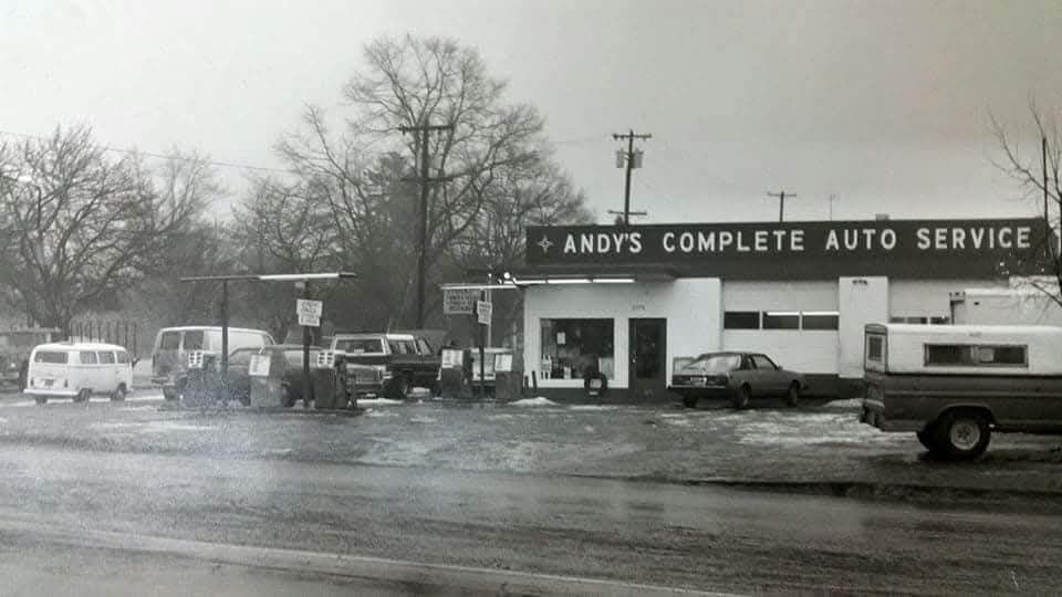 A black-and-white photo of Andy's Complete Auto Service, a service station with parked vehicles on a gray, overcast day.