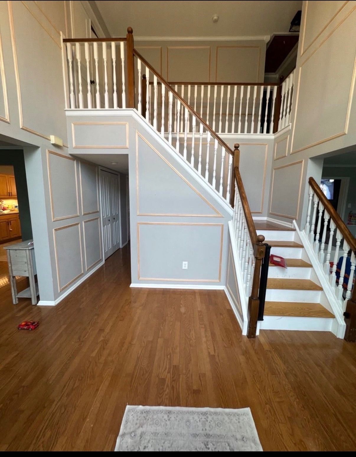 Two-story foyer with hardwood floors, white staircases, and upper balcony railing