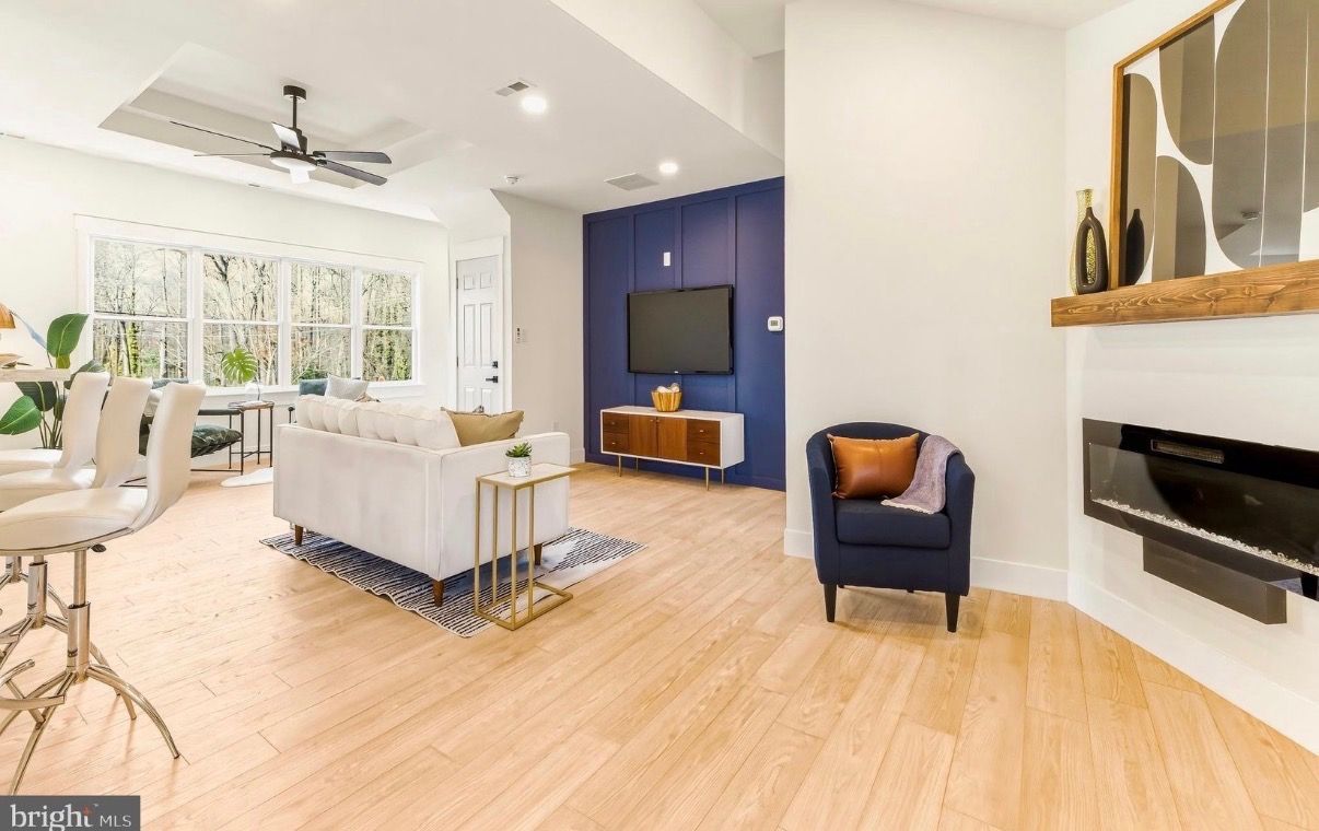 Bright modern living room with white sofa, blue accent wall, fireplace, and large windows