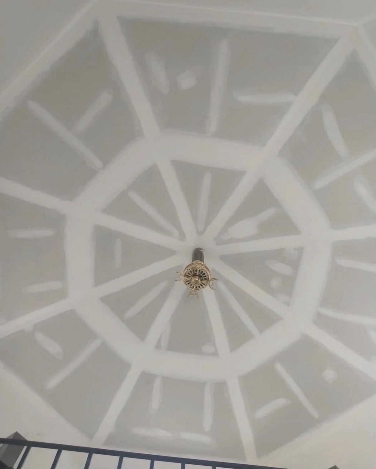 White ceiling light on a patterned white ceiling, viewed from below.