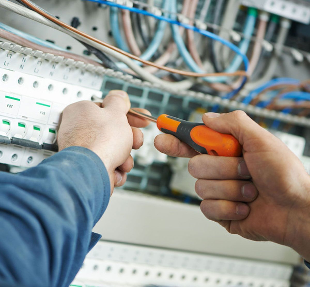 Technician using a screwdriver to wire an electrical control panel