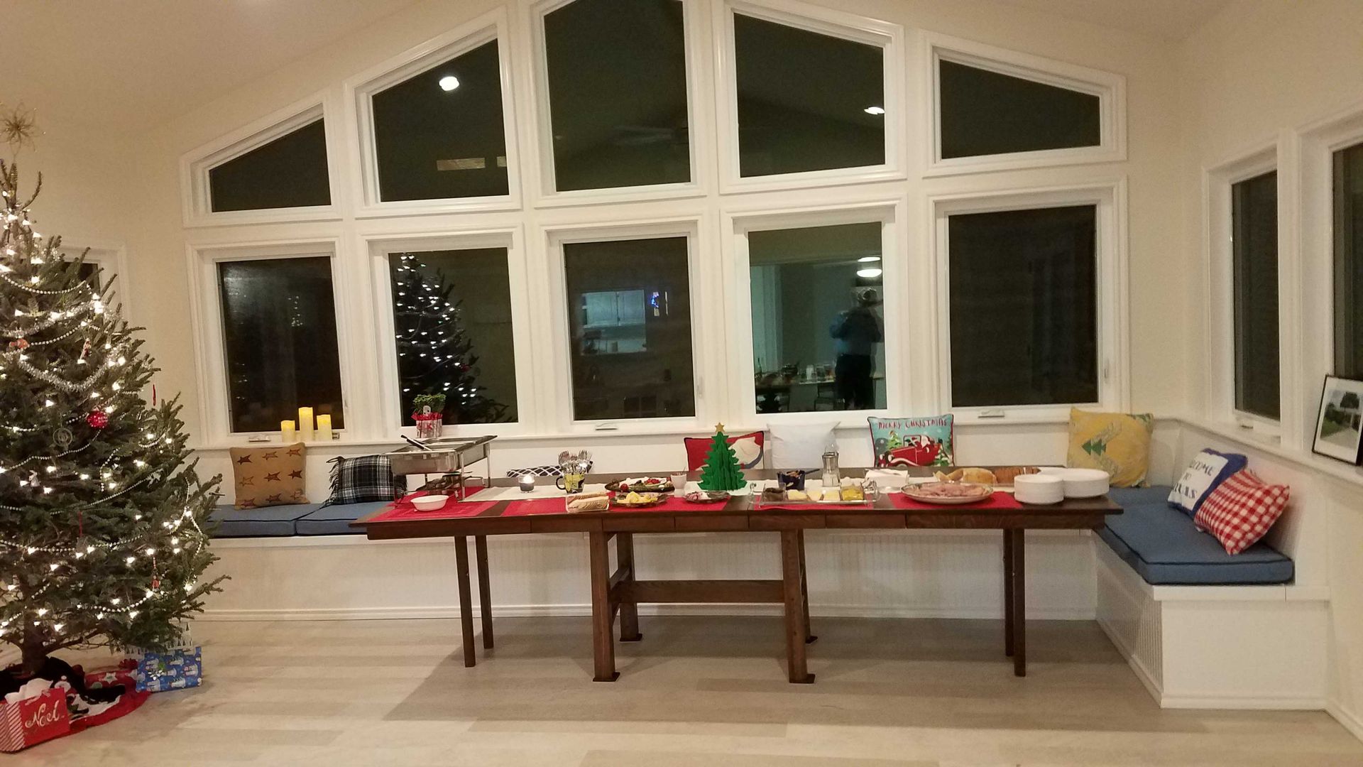 A living room with a christmas tree and a table with food on it.