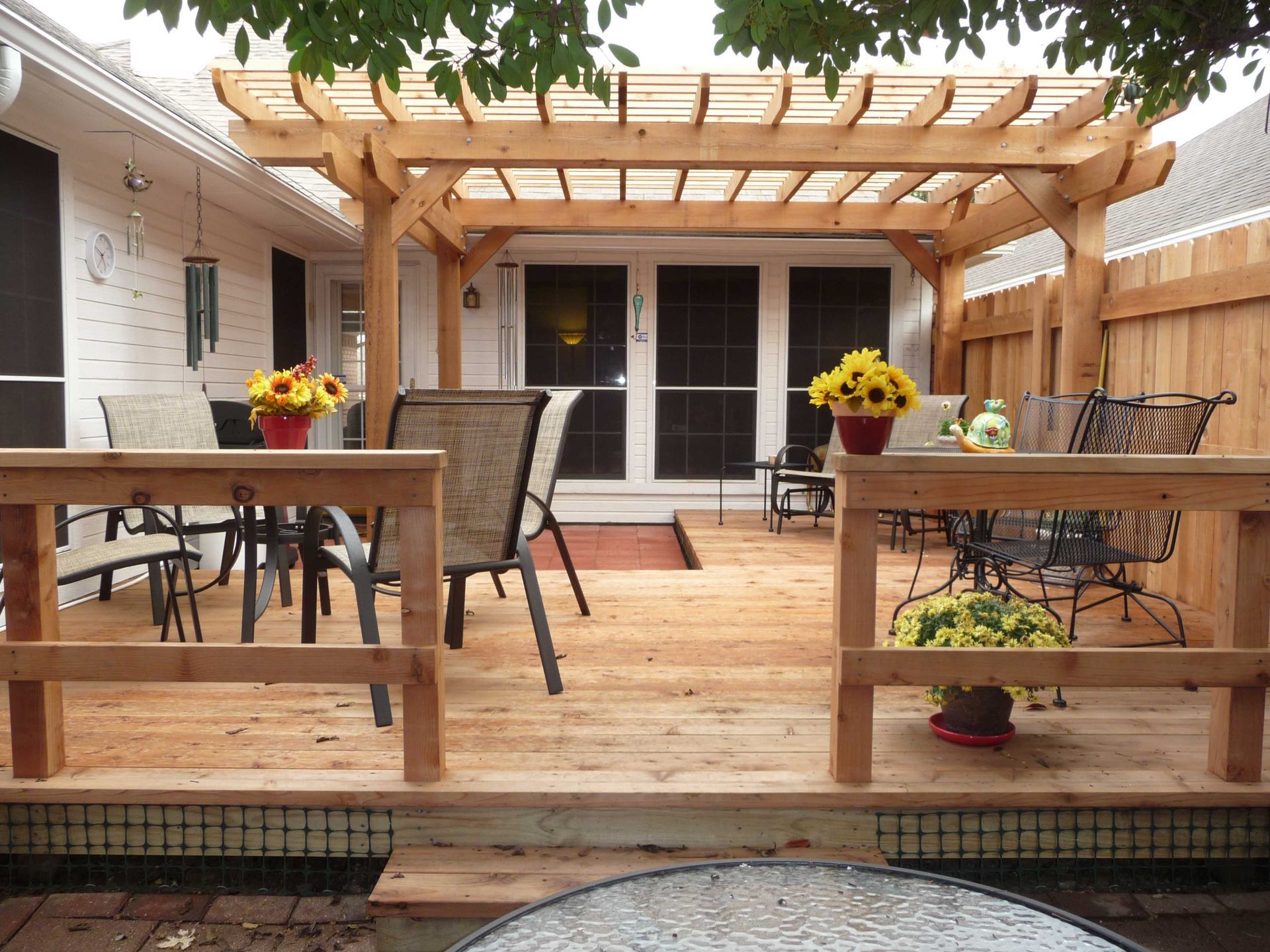 A wooden deck with chairs and a table under a pergola