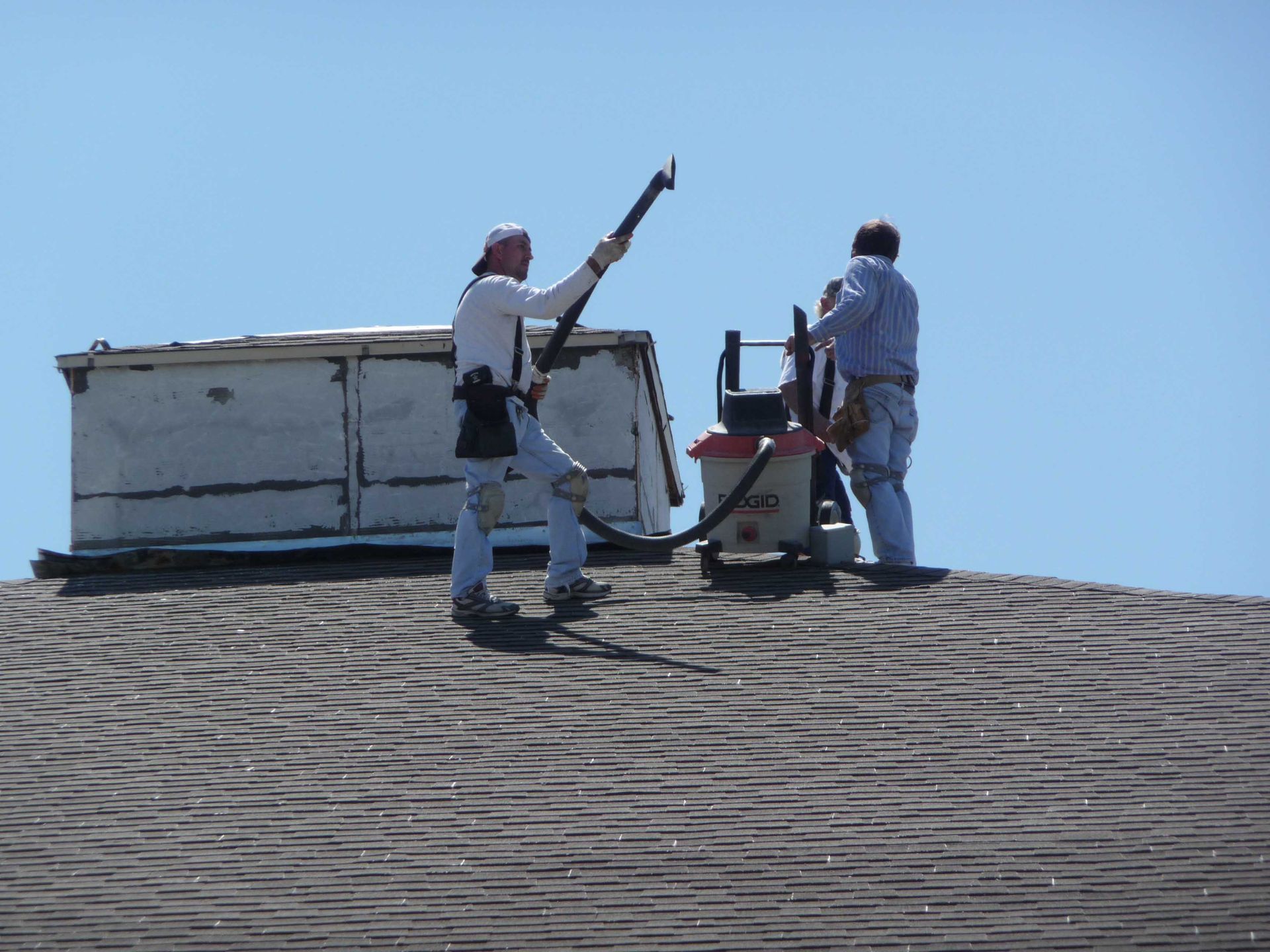 Two men are working on a roof with a vacuum cleaner