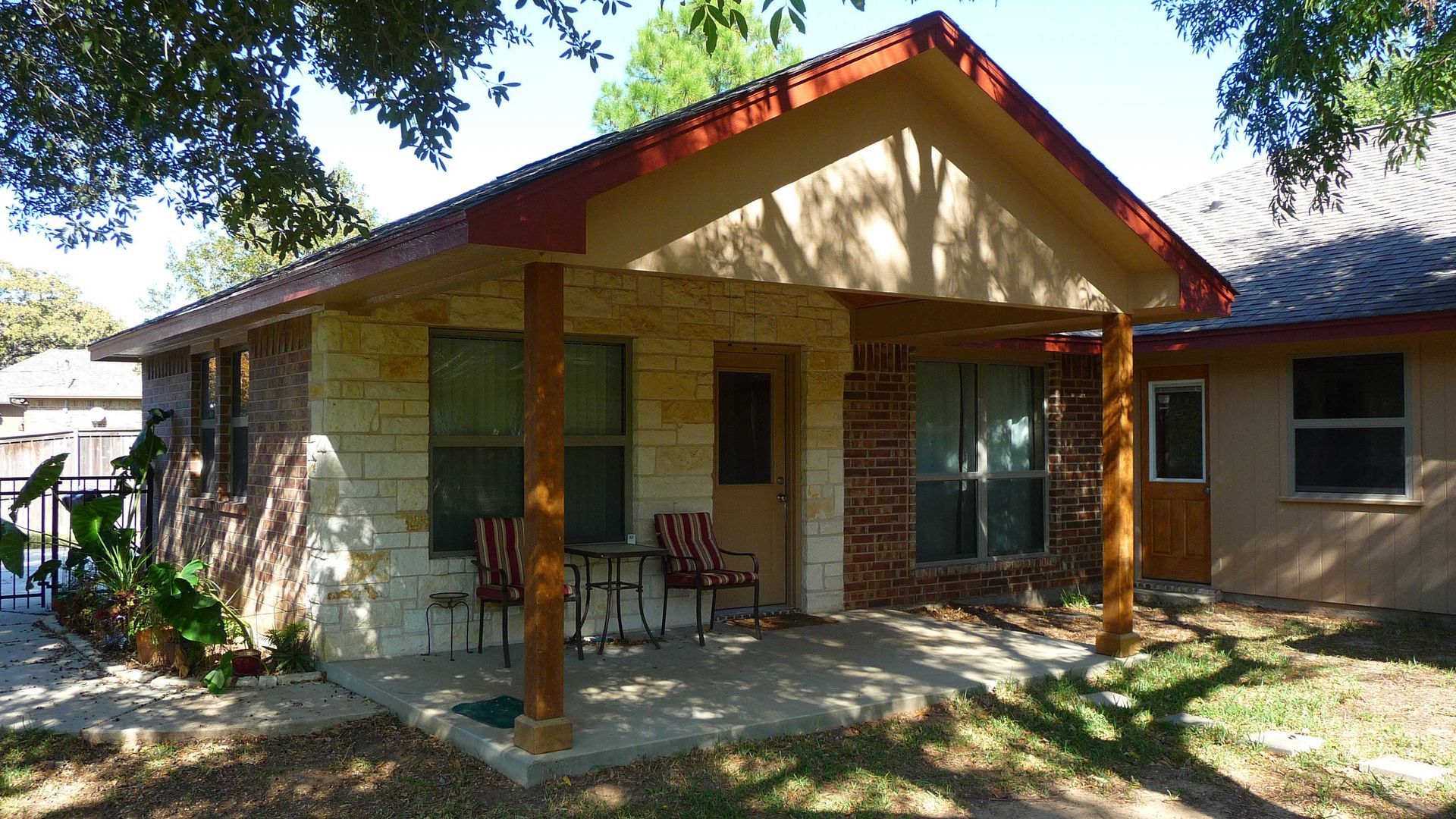 A small house with a porch and chairs in front of it