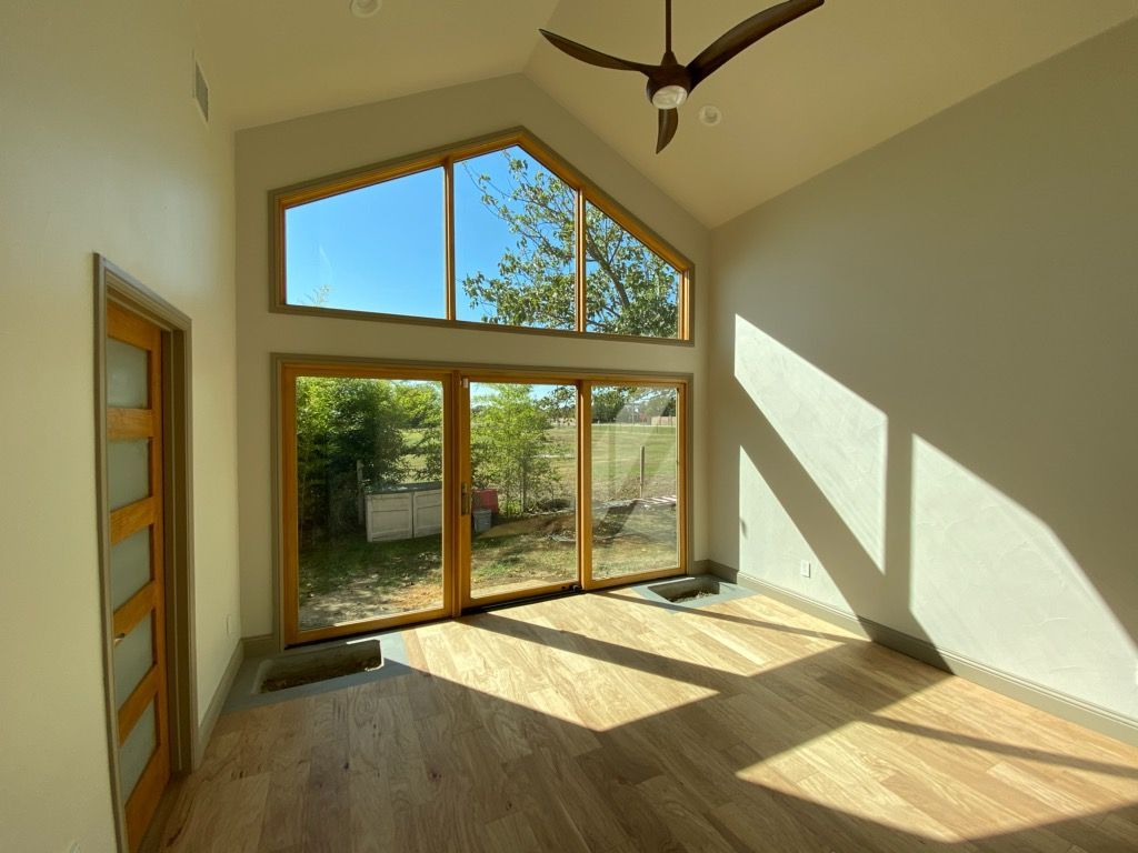 An empty room with a lot of windows and a ceiling fan