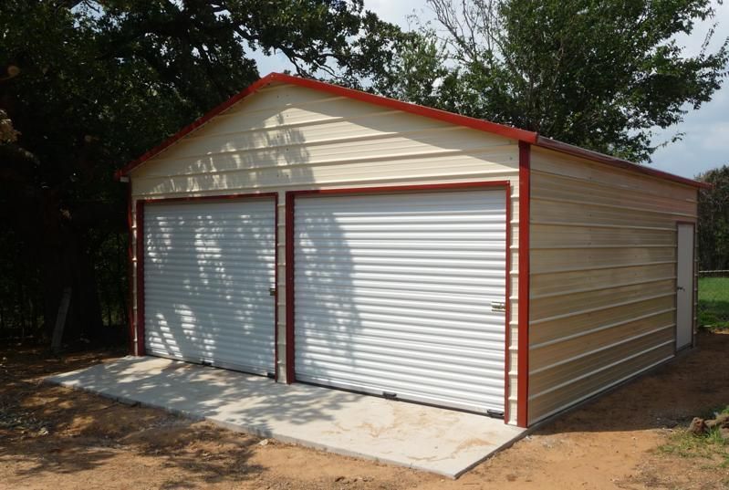 A metal garage with two garage doors and a red roof.