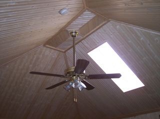 A wooden ceiling with a ceiling fan and a skylight