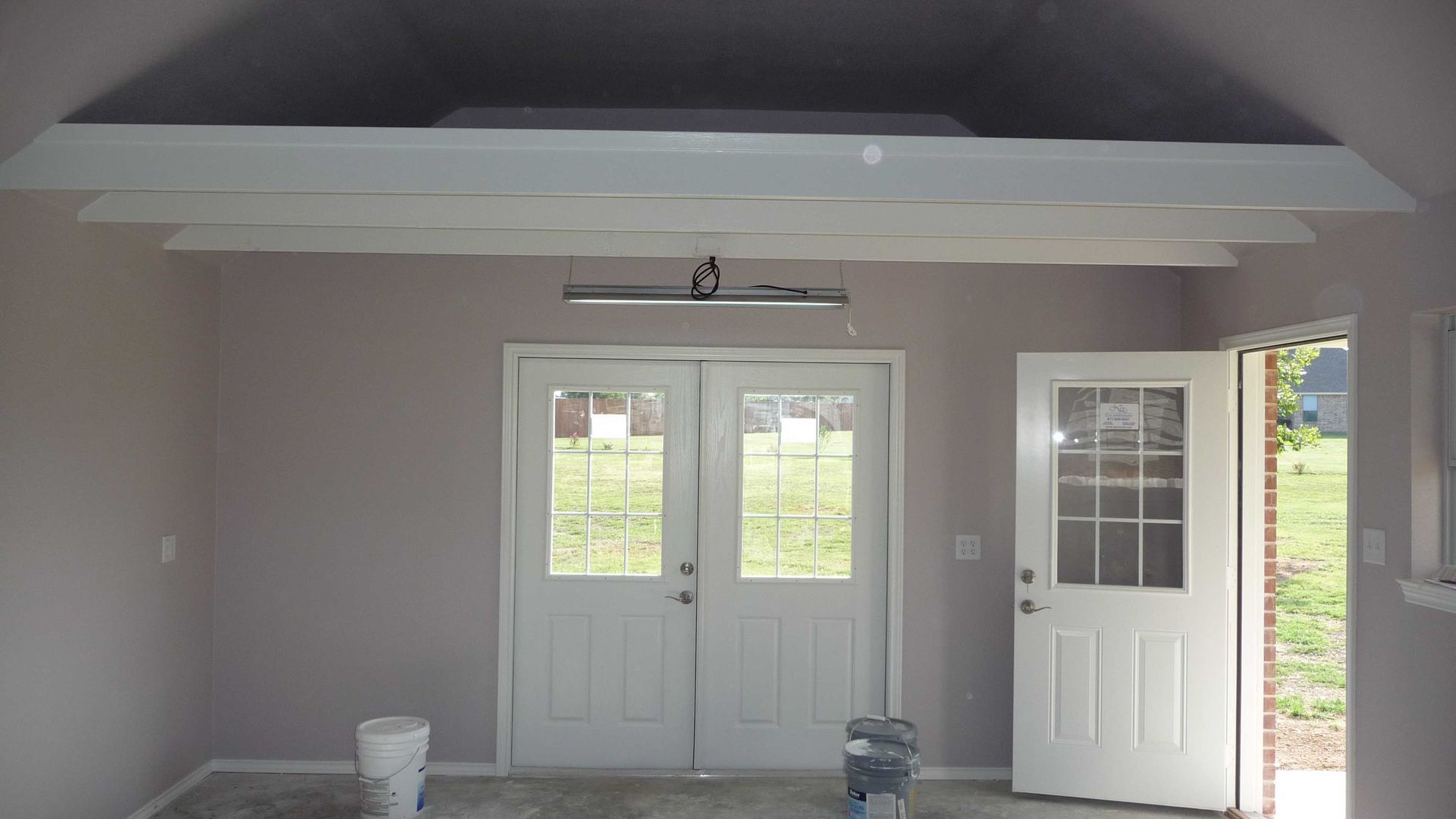 An empty room with white doors and a bucket on the floor
