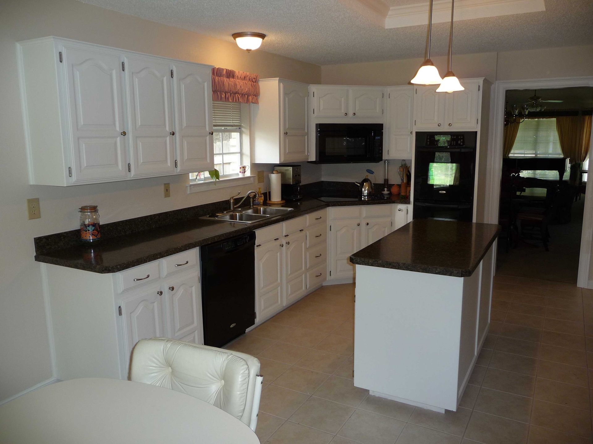 A kitchen with white cabinets and black counter tops