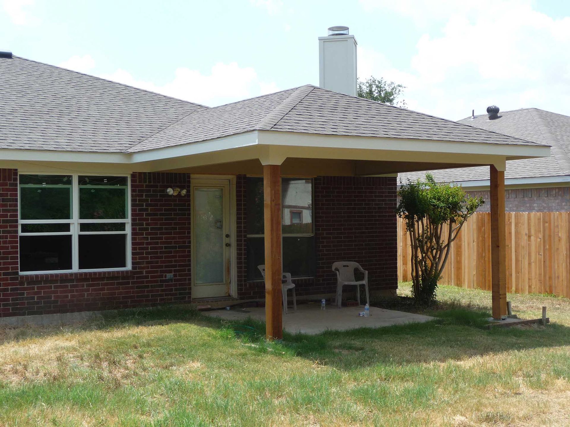 A brick house with a covered porch in the backyard
