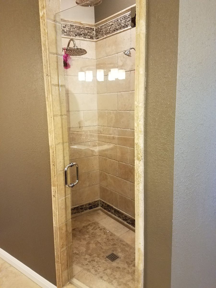 A bathroom with a walk in shower with a glass door.