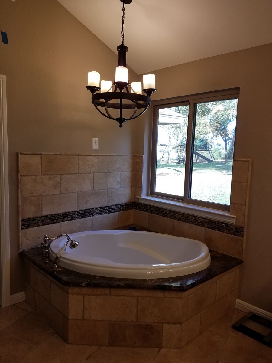 A bathtub in a bathroom with a chandelier hanging from the ceiling