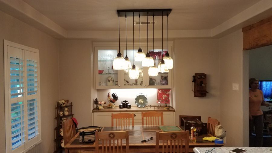 A dining room with a table and chairs and a chandelier hanging from the ceiling.