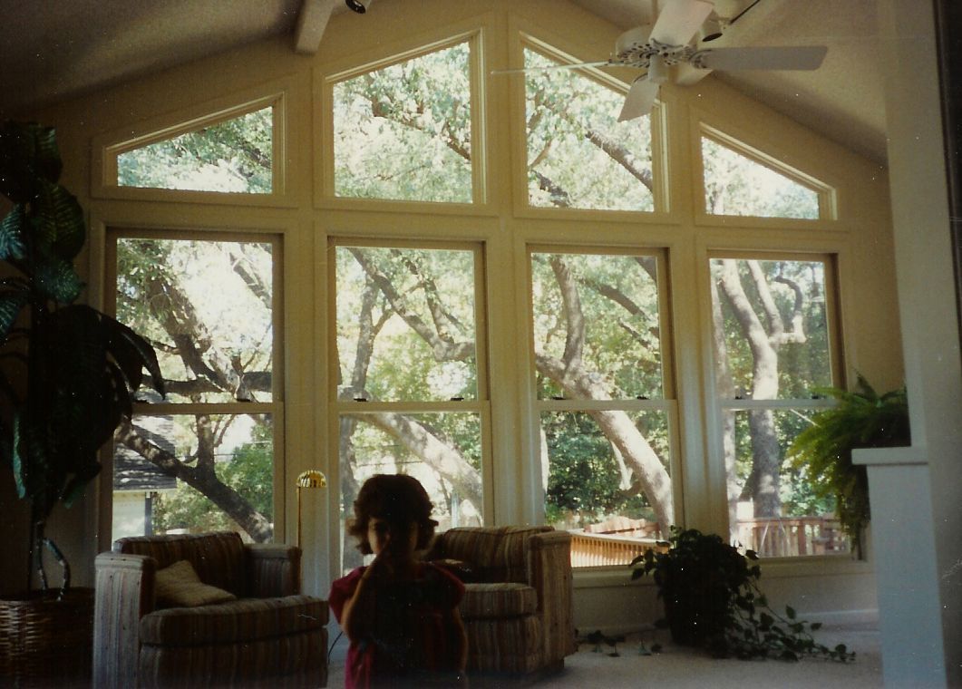 A living room with a lot of windows and a ceiling fan