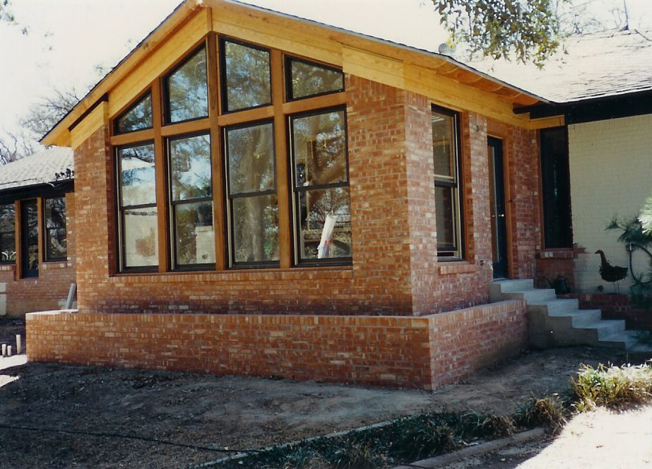 A brick house with a wooden roof and lots of windows
