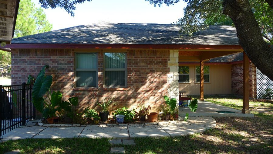 A brick house with a porch and a tree in front of it