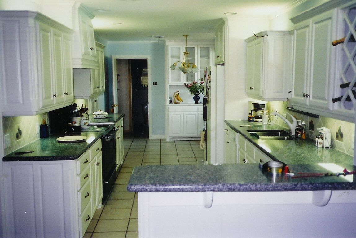 A kitchen with white cabinets and green counter tops