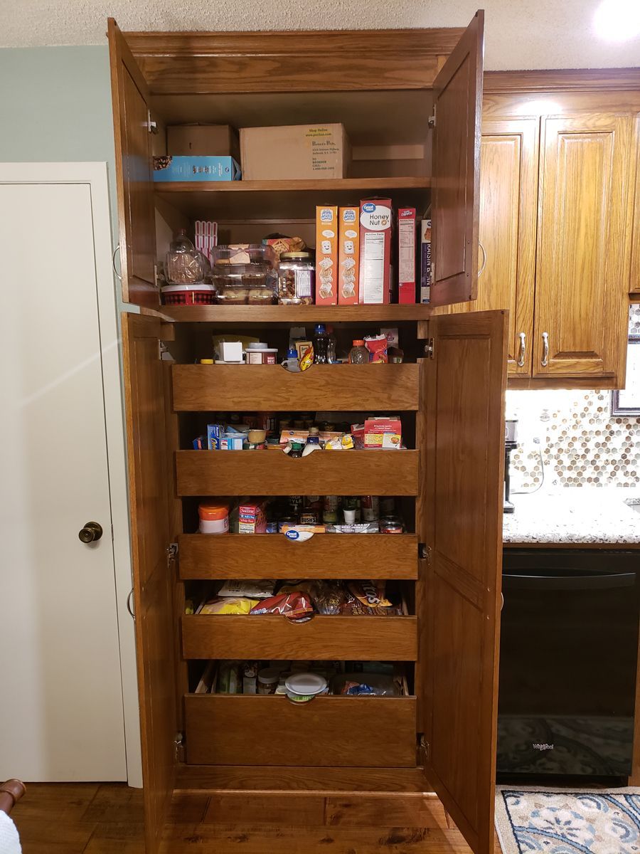 A pantry with drawers and shelves filled with food in a kitchen.