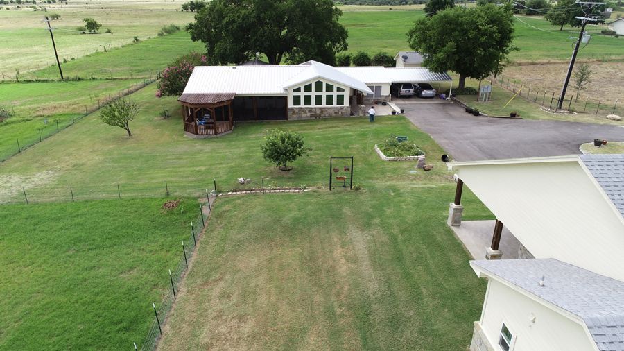 An aerial view of a house in the middle of a grassy field.