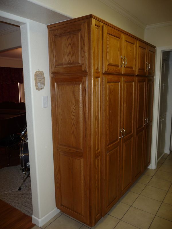 A large wooden cabinet in a hallway next to a door