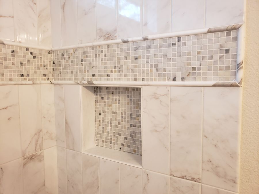 A bathroom with marble tiles and a shower niche.